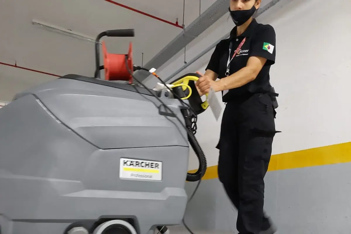 Colaboradora da Boxer operando uma lavadora industrial em uma garagem